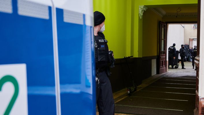 Ein Polizist steht bei einem Einsatz in einem Hauseingang. (Quelle: dpa/Annette Riedl)