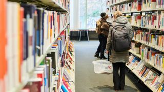 Zwei Besucherinnen stehen zwischen Bücherregalen in der Zentral- und Landesbibliothek Berlin