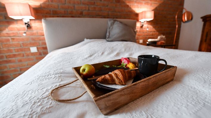 Ein Tablett mit einem Frühstück steht in einer Ferienwohnung auf dem Bett im Schlafzimmer. (Quelle: dpa/Jens Kalaene)