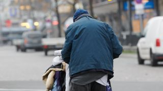 Eine obdachloser Mann läuft mit einem Einkaufswagen mit Jacken und Decken am Zoologischen Garten über die Straßen. Quelle: Annette Riedl/dpa