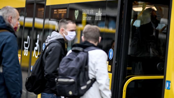 Fahrgäste, die eine Mund und Nasenbedeckung tragen, steigen in einen Bus (Quelle: dpa/Britta Pedersen)