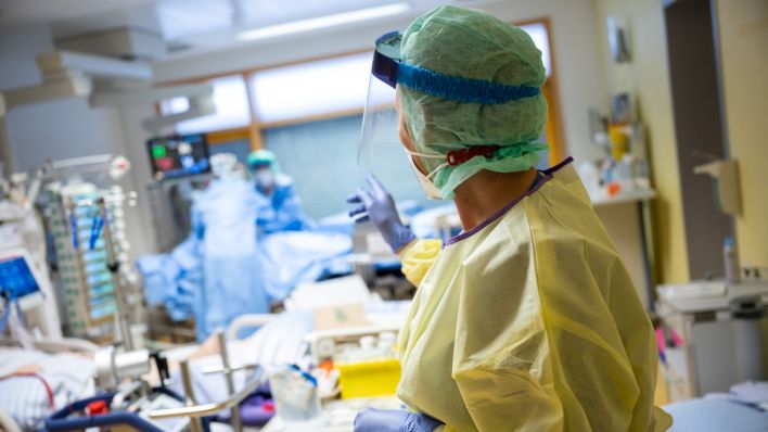 Eine Intensivkrankenschwester steht auf einer Intensivstation eines Klinikum im Zimmer eines Covid-19-Patienten. (Quelle: dpa/Sebastian Gollnow)