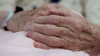 Symbolbild: Gefaltete Hände eines alten Mannes liegen am 04.10.2016 in der Mehrgenerationenhospiz der Heilhaus-Stiftung Ursa Paul in Kassel (Hessen) auf einer Bettdecke. (Quelle: dpa/Swen Pförtner)