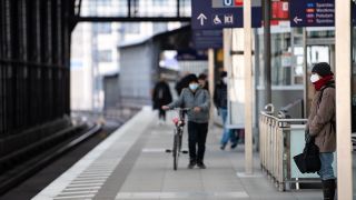 Fahrgäste mit Mund-Nasen-Bedeckungen warten am Bahnhof Friedrichstraße in Mitte auf eine S-Bahn (Bild: dpa/Bernd von Jutrczenka)
