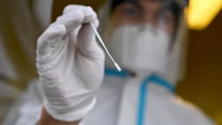 Ein medizinischer Mitarbeiter führt einen Rachenabstrich für einen SARS-CoV-2-Antigentest. (Quelle: dpa/Britta Pedersen)