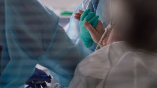 Symbolbild: Eine Ärztin hält in der Intensivstation die Hand eines Coronapatienten. (Quelle: dpa/Henning Kaiser)