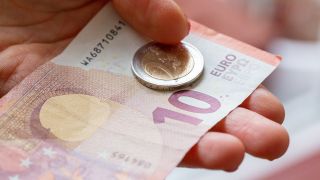 Symbolbild: Eine Person hält 12 Euro in der Hand. Der gesetzliche Mindestlohn in Deutschland soll zum 1. Oktober 2022 auf zwölf Euro steigen. (Quelle: dpa/F. Juarez)