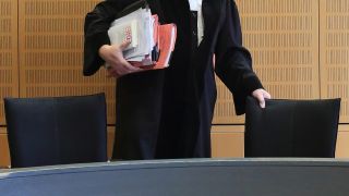 Ein Richter rückt sich zum Auftakt eines Prozesses in einem Verhandlungssaal seinen Stuhl zurecht. (Quelle: dpa/Jens Wolf)