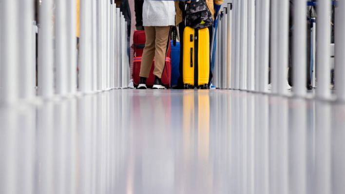 Reisende warten vor einem Check-In-Schalter am Flughafen. (Quelle: dpa/Rolf Vennenbernd)