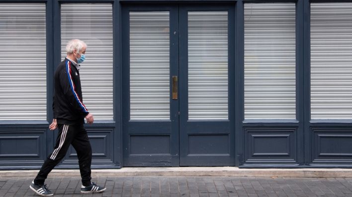 Ein Mann geht an einem geschlossenen Laden vorbei (Quelle: dpa/Joe Giddens)