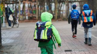 Drei Schüler gehen am 22.02.2021 mit Schulranzen zum Eingang einer Grundschule in Prenzlauer Berg. (Quelle: dpa/Annette Riedl)