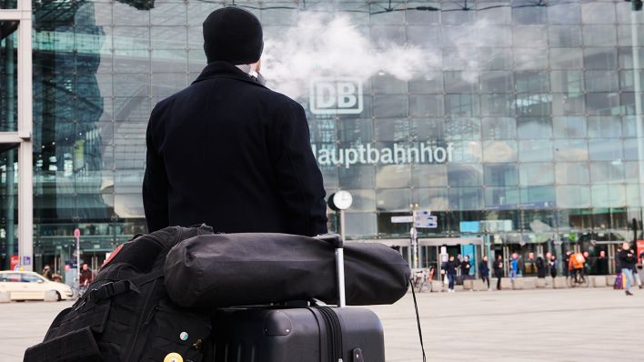 Ein Mann raucht eine E-Zigarette, während er mit seinem Gepäck vor dem Berliner Hauptbahnhof steht (Quelle: dpa/Annette Riedl)