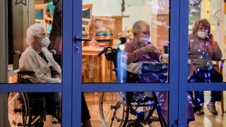 Archivbild: Bewohnerinnen eines Seniorenzentrums in Jüterbog beobachten hinter Fensterscheiben sitzend mit Mund-Nasen-Schutz einen Weihnachtsauftritt (Bild: dpa/Christoph Soeder)
