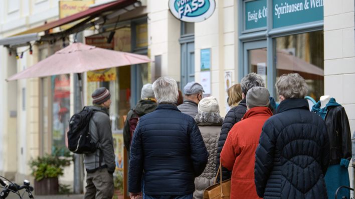 Passanten warten vor einem Geschäft "Spirituosen und Weine" vor dem Schild "Vom Fass" in der Potsdamer Innenstadt (Bild: dpa/Soeren Stache)