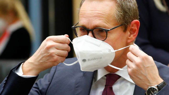 Berlins Regierender Bürgermeister Michael Müller zieht sich eine Schutzmaske vor Mund und Nase (Quelle: Reuters/Fabrizio Bensch)