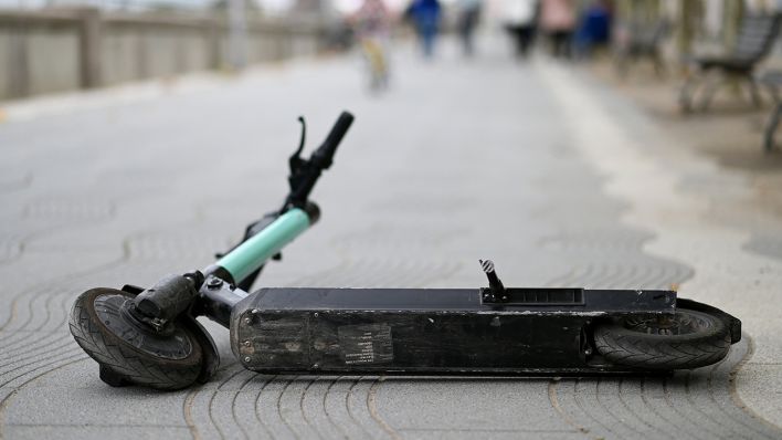 Symbolbild: Einumgefallener E-Scooter liegt auf einem Gehweg (Bild: dpa/Frank May)