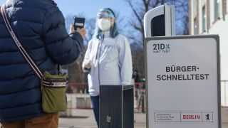 Eine Mitarbeiterin der Betreiber-Firma 21Dx GmbH und ein Bürger stehen vor einem Corona-Schnelltestzentrum. (Quelle: dpa/Jörg Carstensen)
