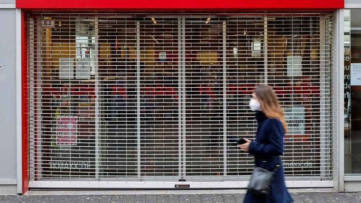 Frau mit Maske geht an einem geschlossenen Geschäft vorbei (Quelle: Rupert Oberhäuser)