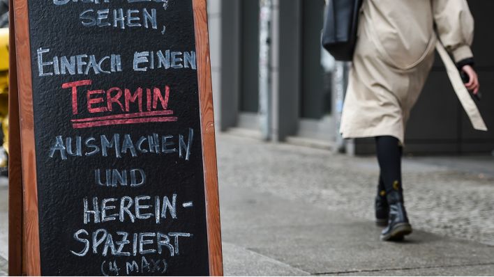 Vor einem Geschäft steht ein Schild mit der Aufschrift „Schee’n dich zu sehen, einfach einen Termin ausmachen und hereinspaziert“. Quelle: Kira Hofmann/dpa