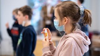 Eine Schülerin einer vierten Klasse einer Grundschule, hält während eines selbst durchgeführten Coronatests ihr Teströhrchen mit ihrer Speichelprobe in den Händen. Quelle: dpa/Matthias Balk