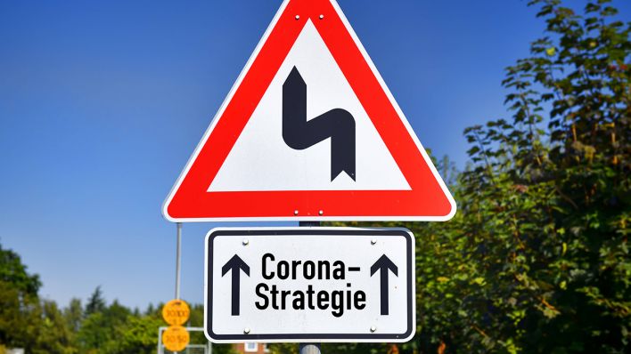 Symbolbild: Schild mit Kurvensymbol und Aufschrift Corona-Strategie. (Quelle: imago images/C. Ohde)