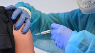 Spritze mit Impfstoff gegen Covid-19 im Arm einer Person (Bild: imago images / Sven Simon)