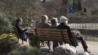 Menschen mit Schutzmasken sitzen in einem Berliner Park in der Sonne (Quelle: imago images/Kremming)