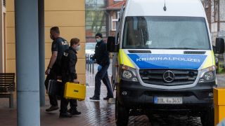 Ein Mitarbeiter der Kriminalpolizei geht mit zwei kleinen Handkoffern auf dem Gelände einer Potsdamer Klinik zu einem Polizeiauto. In der Klinik sind vier Leichen gefunden worden. (Quelle: dpa/Christophe Gateau)