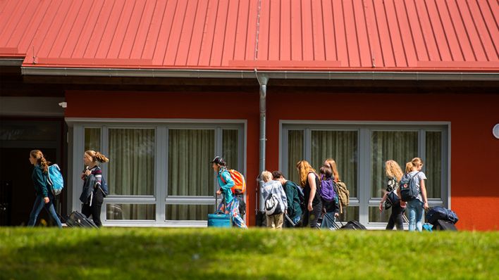 Archivbild: Eine Gruppe Schüler*innen geht im Juni 2018 mit ihrem Gepäck an einer Unterkunft vorbei (Bild: dpa/Andreas Arnold)