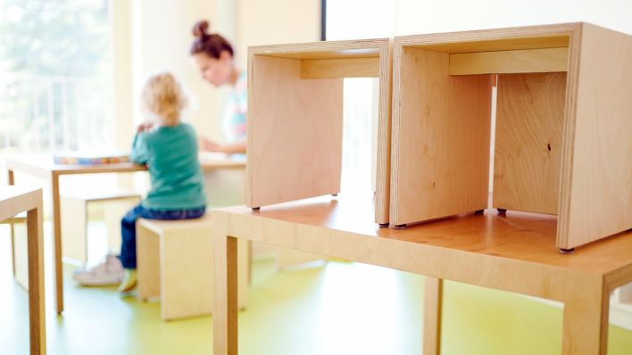 Eine Erzieherin und ein Kind spielen in einem städtischen Kindergarten hinter auf den Tisch gestellten Stühlen (Quelle: DPA/Uwe Anspach)