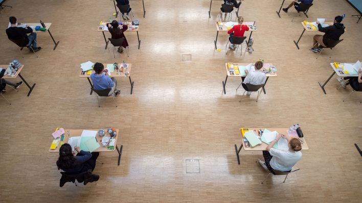 Schülerinnen und Schüler sitzen während einer Abiturprüfung mit dem vorgeschriebenen Abstand zueinander in der Aula eines Gymnasiums. (Quelle: dpa/Marijan Murat)