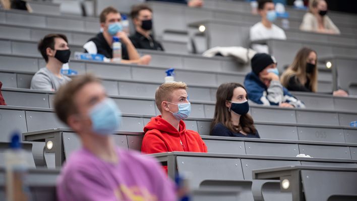 Studierende mit Mund- und Nasenmaske sitzen in einem Hörsaal. (Quelle: dpa/Sebastian Gollnow)