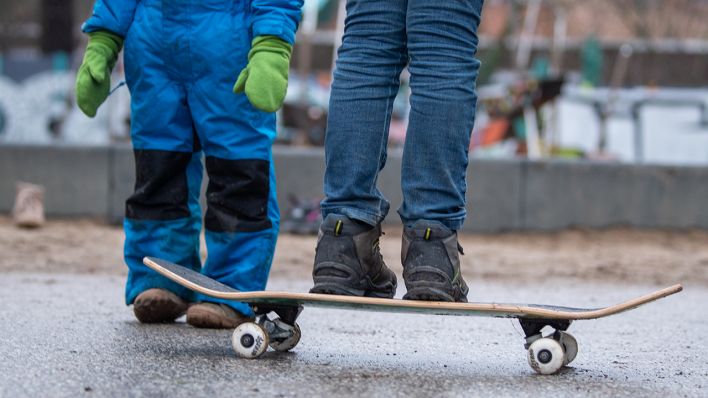 Zwei Kinder stehen bei einem Spielplatz in Berlin. Ein Kind balanciert auf einem Skateboard. (Quelle: dpa/Dorothée Barth)