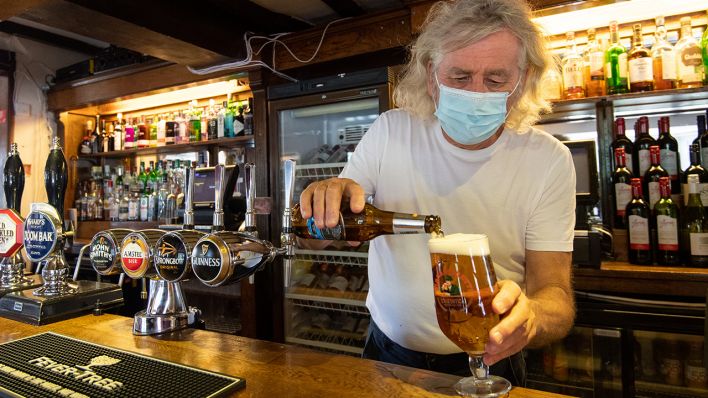 Symbolbild: Ein Barbesitzer schenkt Flaschenbier in ein Glas aus. (Quelle: dpa/J. Giddens)