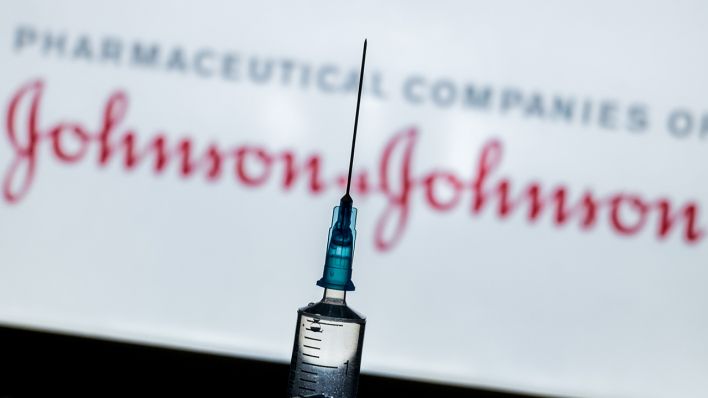 Symbolbild: Eine Impfspritze vor dem Hintergrund des Johnson & Johnson Logos. (Quelle: dpa/A. Ronchini)