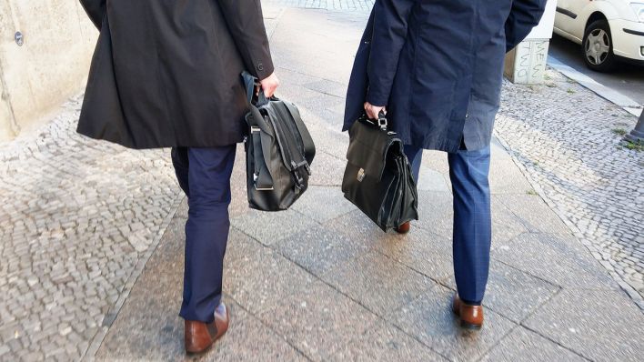 05.11.2018, Berlin: Zwei Männer in Anzügen und Mänteln tragen Aktentaschen und gehen im Bezirk Mitte über einen Bürgersteig. (Quelle: dpa/Wolfram Steinberg)