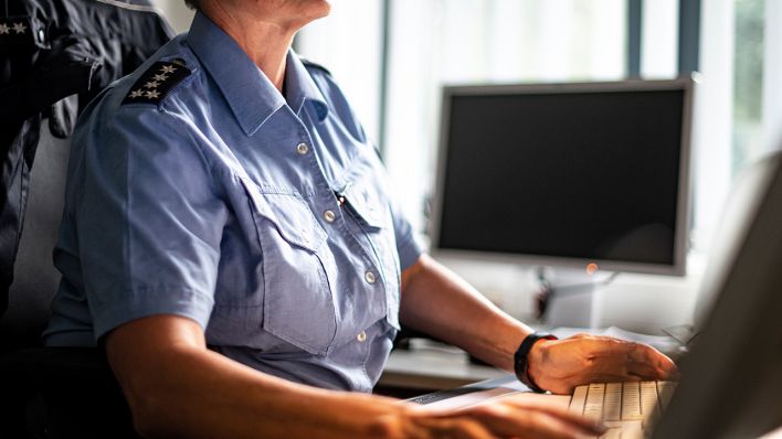 Symbolbild: Eine Polizistin sitzt in ihrem Büro an ihrem PC und Laptop. (Quelle: dpa/F. Sommer)