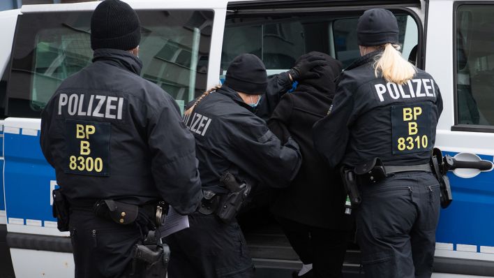 Symbolbild: Nach einer Razzia in Berlin nehmen PolizistInnen eine verdächtige Person fest. (Quelle: dpa/P. Zinken)