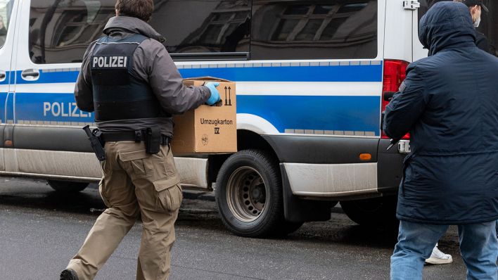 Symbolbild: Ein Polizist trägt bei einer Razzia eine Kiste. (Quelle: dpa/Christophe Gateau)