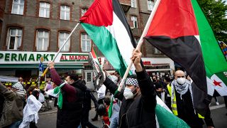 Teilnehmer der Demo verschiedener palästinensischer Gruppen laufen am 15. Mai 2021 mit Palästina-Flaggen durch Berlin-Neukölln. (Quelle: dpa/Fabian Sommer)