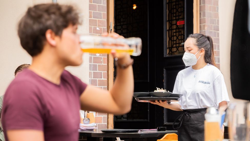 Thuy Nhi Nguyen, Kellnerin, trägt am 24.05.2021 im Berliner Bezirk Prenzlauer Berg in einem Restaurant für asiatische Fusionsküche ein Tablett. (Quelle: dpa/Christoph Soeder)