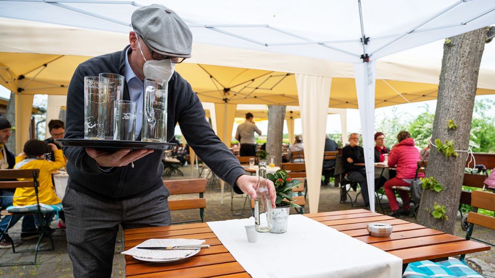 Mario Kade räumt auf der Terrasse seines Restaurants einen Tisch ab. Seit dem 21. Mai gelten in weiten Teilen Brandenburgs verschiedene Lockerungsregelungen. (Quelle: dpa/Christophe Gateau)