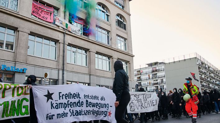"Freiheit entsteht als kämpfende Bewegung - für mehr Staatszerlegung" steht auf dem Transparent, das Demonstranten der linken Szene halten, während sich Anwohner mit farbigem Rauch aus den Fenstern solidarisieren (Quelle: DPA/Annette Riedl)