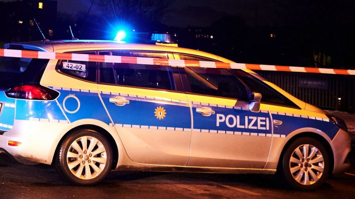 Symbolbild: Das Blaulicht eines Polizeiwagens hinter einem Absperrband, leuchtet. (Quelle: dpa/A. Riedl)