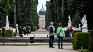 Besucher gehen durch den Park des Schlosses Sanssouci. (Quelle: dpa/Britta Pedersen)