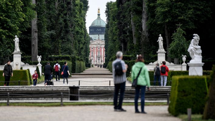 Besucher gehen durch den Park des Schlosses Sanssouci. (Quelle: dpa/Britta Pedersen)