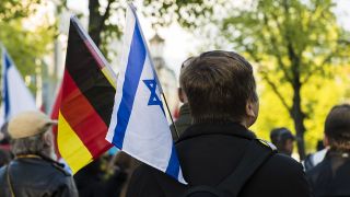 Symbolbild: Auf einer Demo hält eine Teilnehmerin eine deutsche und eine israelische Flagge in der Hand. (Quelle: dpa/J. Scheunert)