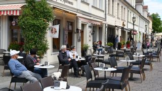 Bei strahlender Sonne sitzen Gäste vor einer Gaststätte in der Brandenburger Straße in Potsdam. Quelle: dpa/Bernd Settnik