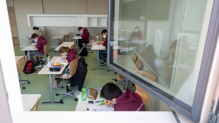 Schülerinnen und Schüler mit medizinischen Masken in einem Klassenzimmer. (Quelle: dpa/S. Gollnow)