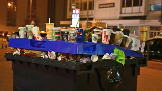 Symbolbild: Eine überfülte Mülltonne mit überwiegend To-Go-Müll in einer Innenstadt. (Quelle: dpa/D. Kubirski)